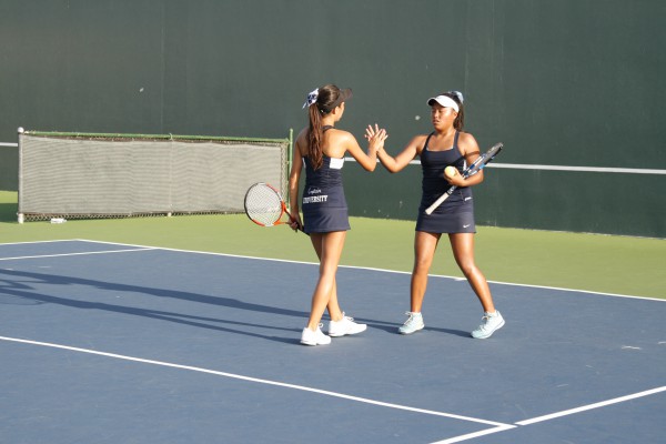 Doubles partners Anja Seng (Sr.) and Kayla Agustin (So.) high-five after a point. (Danya Clein)