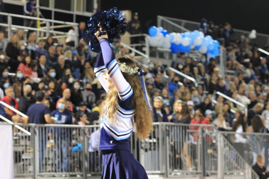 This image displays a cheerleader cheering on the student population during the Homecoming Game.