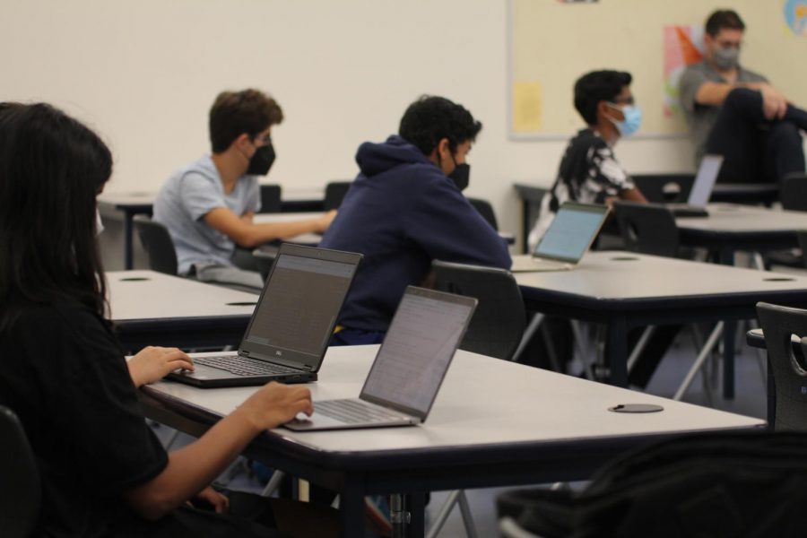 Students attend the Computer Science Club meeting and take notes as a board member lectures.