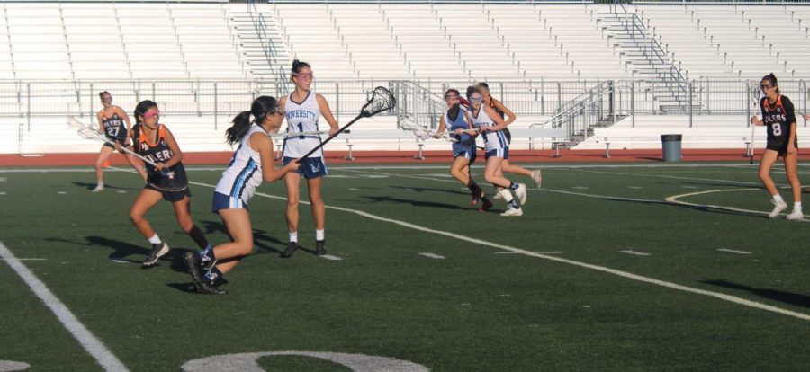UHS girls lacrosse athlete attempting to score a goal against opponent. 