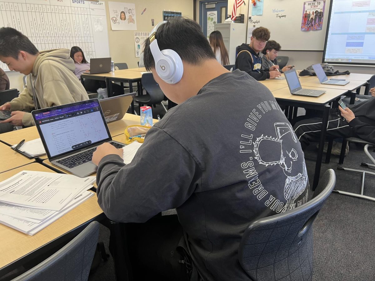 A student wears Apple headphones in class while working on homework. Immersed in their music, headphone users may be unresponsive to surrounding conversations, a common pet peeve of UHS students.