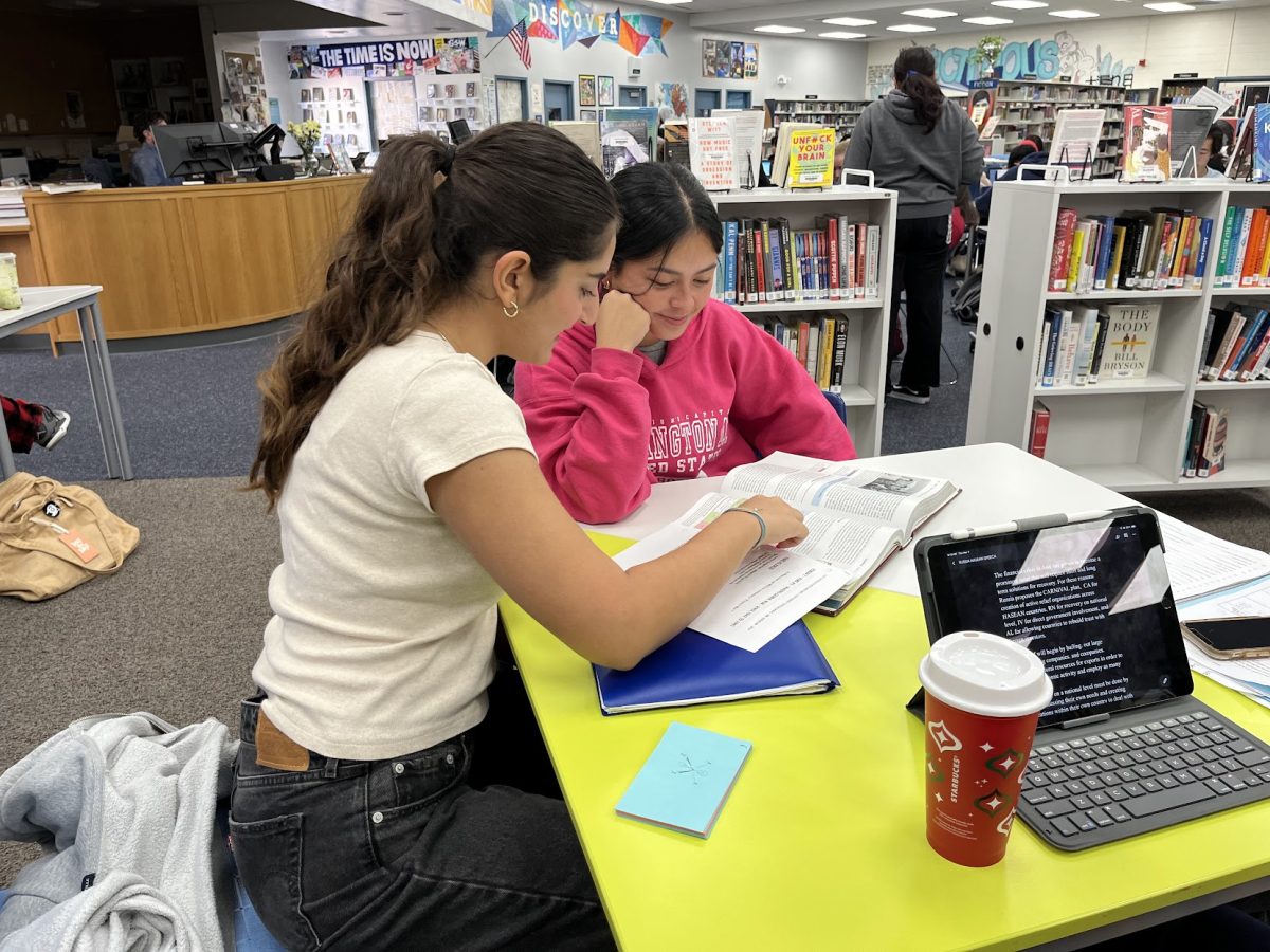 The+UHS+Library+offers+a+peer+tutoring+program+available+after+school%2C+allowing+students+to+connect+with+each+other+and+offer+support+for+a+variety+of+subjects.+Peer+tutor+Nicca+Majdi+helps+sophomore+Natalie+Thomas+with+her+AP+U.S.+History+reading.+