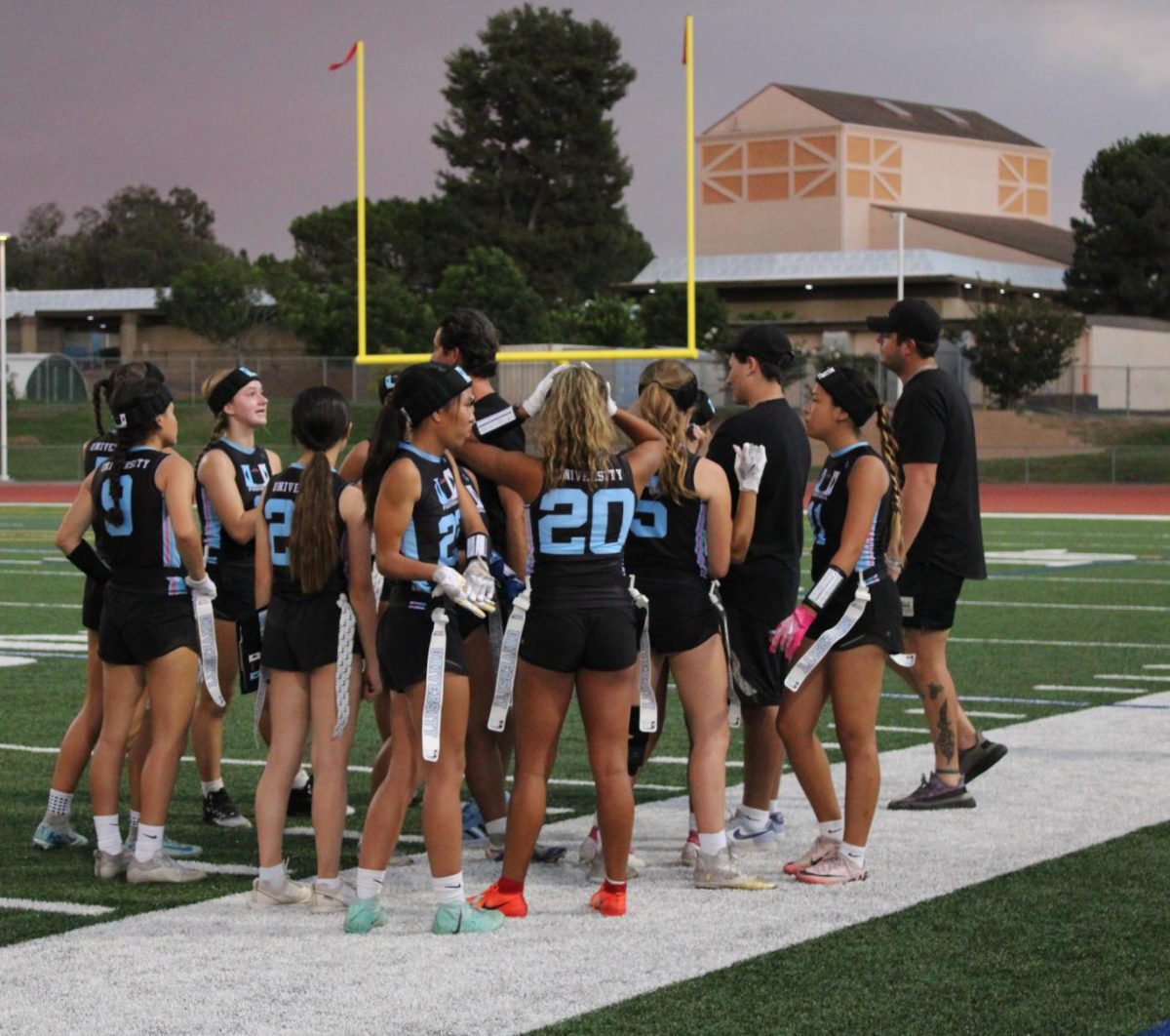 UHS Girls' Flag Football team strategizing in a huddle during their game against Northwood.