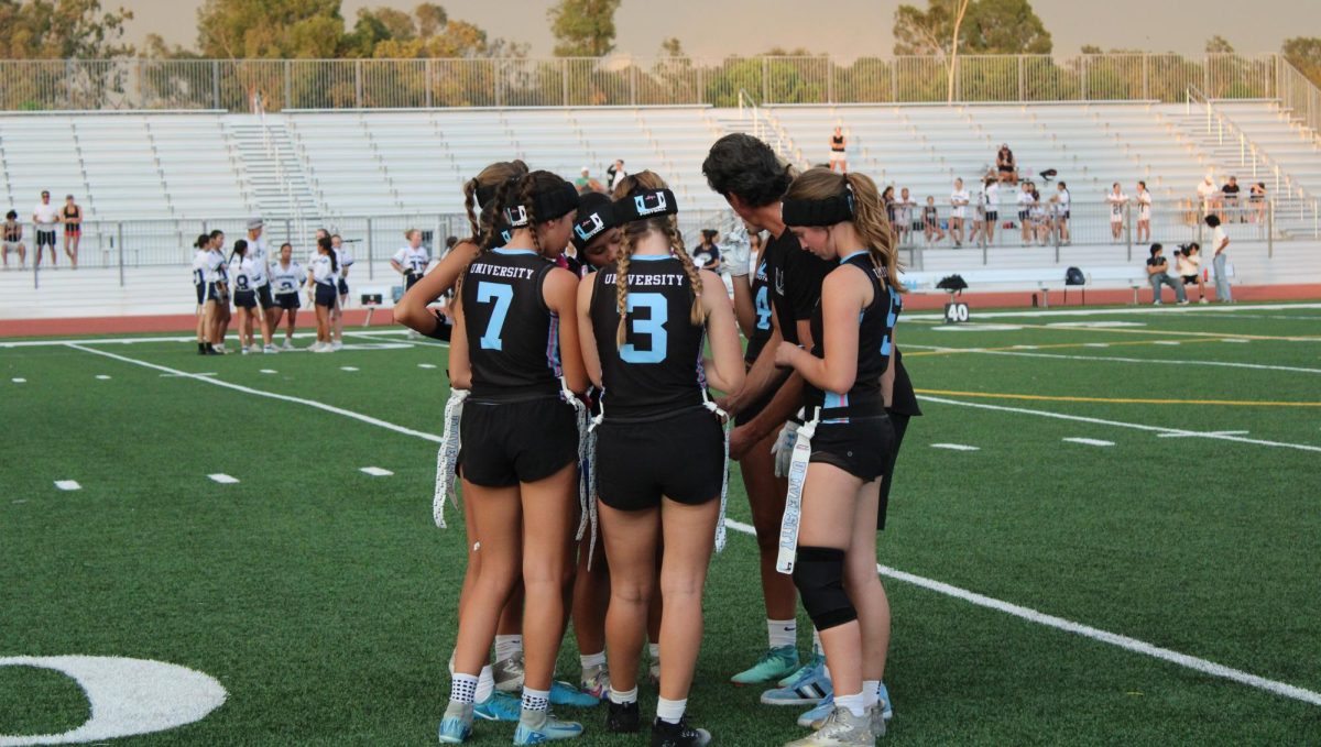 Junior captain Elyse Mills (#3) of Girls' Flag Football joins her team in a huddle.