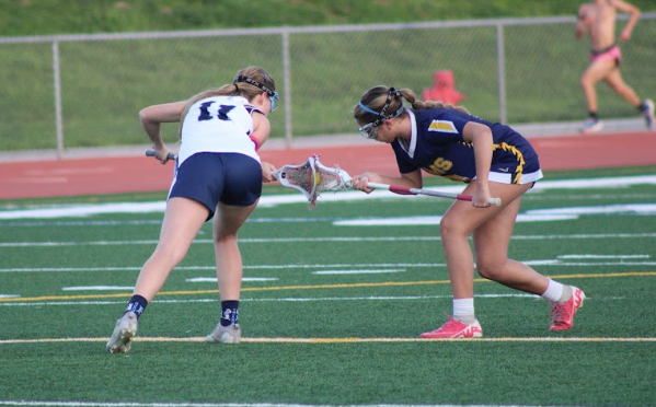 UHS girls' lacrosse player (left) battling against a Millikan player for control of the ball.