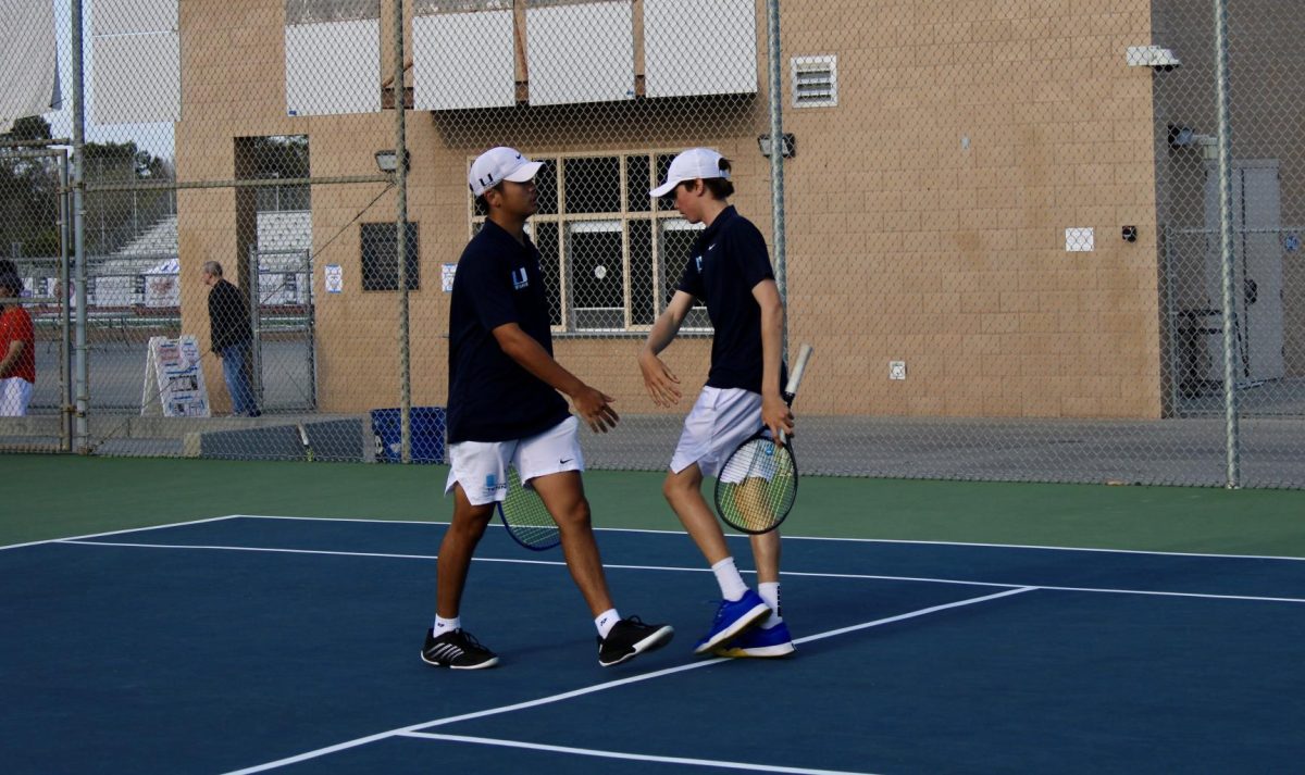 Trojans' doubles pair encourages one another after a crucial point to win the set.